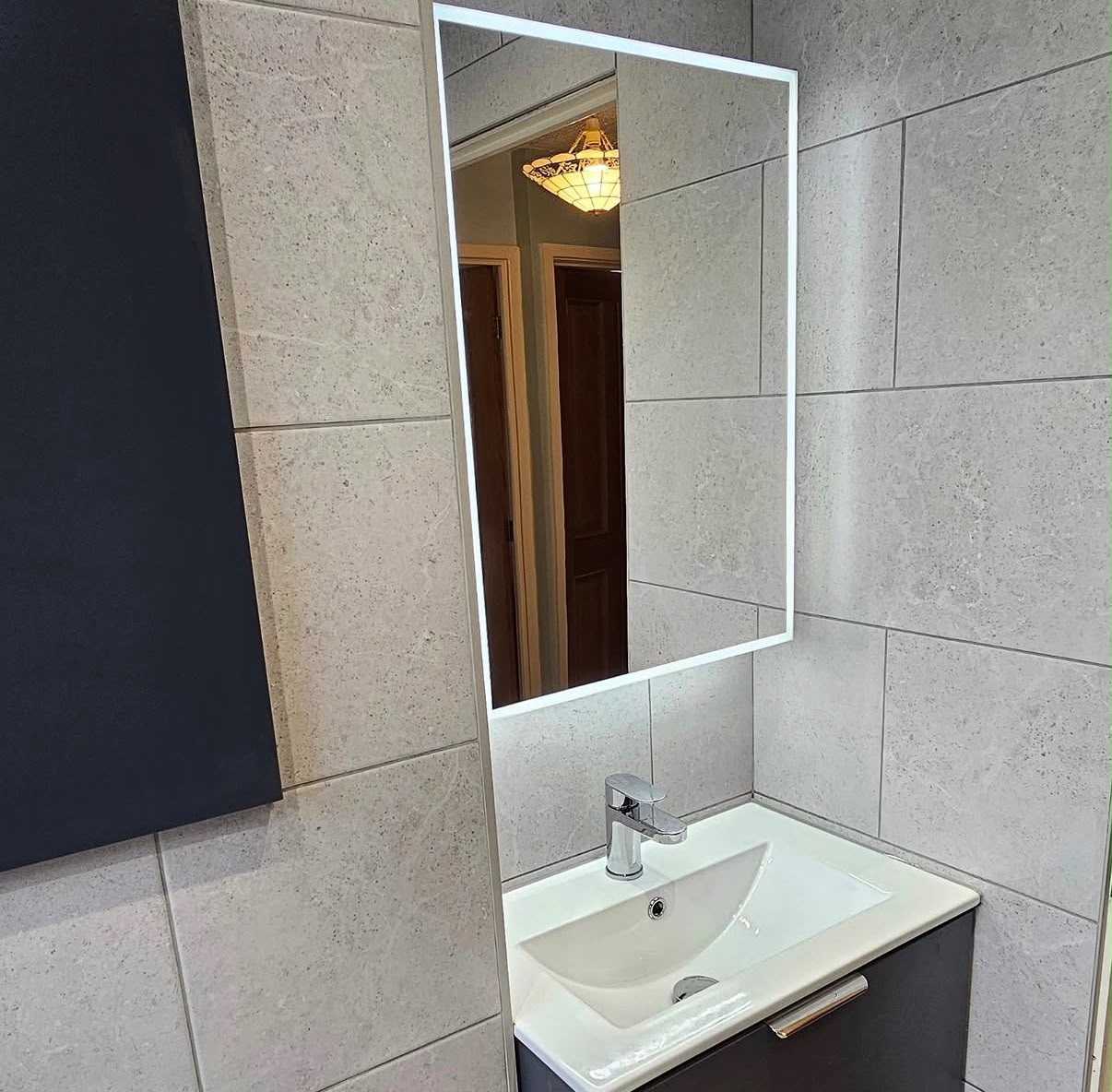 Contemporary bathroom vanity with illuminated mirror, floating charcoal unit and grey stone tiles